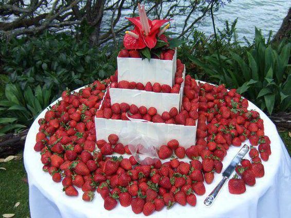 Tiered wedding cake surrounded by fresh strawberries